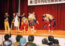 観客の前でお囃子をする人と被り物をかぶった人たちが踊っている写真