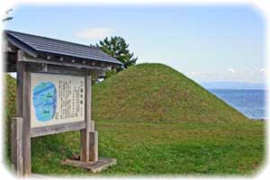 草の生えた盛り土の手前に説明看板が建っている写真