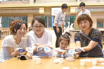 3人の女性と女の子が手作りした作品を見せている写真