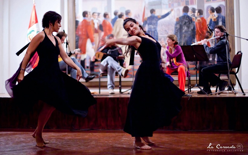 様々な楽器で演奏している人たちの前で黒のドレスを着て踊っている女性2人の写真