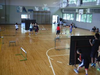 体育館の中で、2つに分かれた卓球台を盾にして子どもたちがスポーツをしている写真