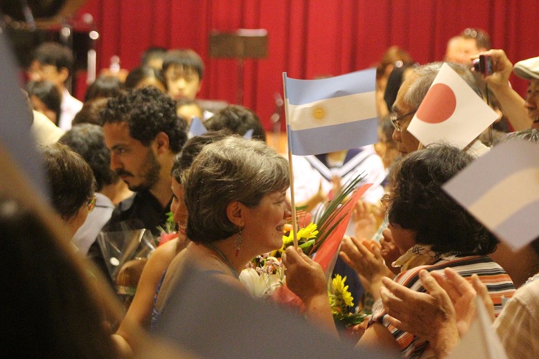 アルゼンチンの国旗や日本の国旗が書かれた手旗を持って交流をしている人たちの写真