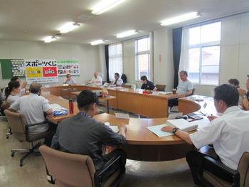 会議室で、細長い楕円型の机に腰掛けた男性数名が会議を開いている写真