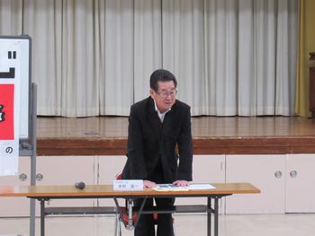 両手のひらを机について話をする眼鏡をかけた男性の写真