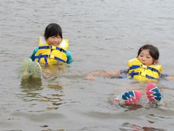 黄色いライフジャケットを着た2人の子供が、足を伸ばして川に浮かんでいる写真