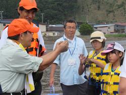 複数名の指導員と黄色いライフジャケットを着た2人の子供が話している写真