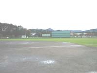 遠景に山や建物が見える野球場の写真