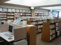 たくさんの本が置かれている複数の本棚とパソコンがある部屋の写真