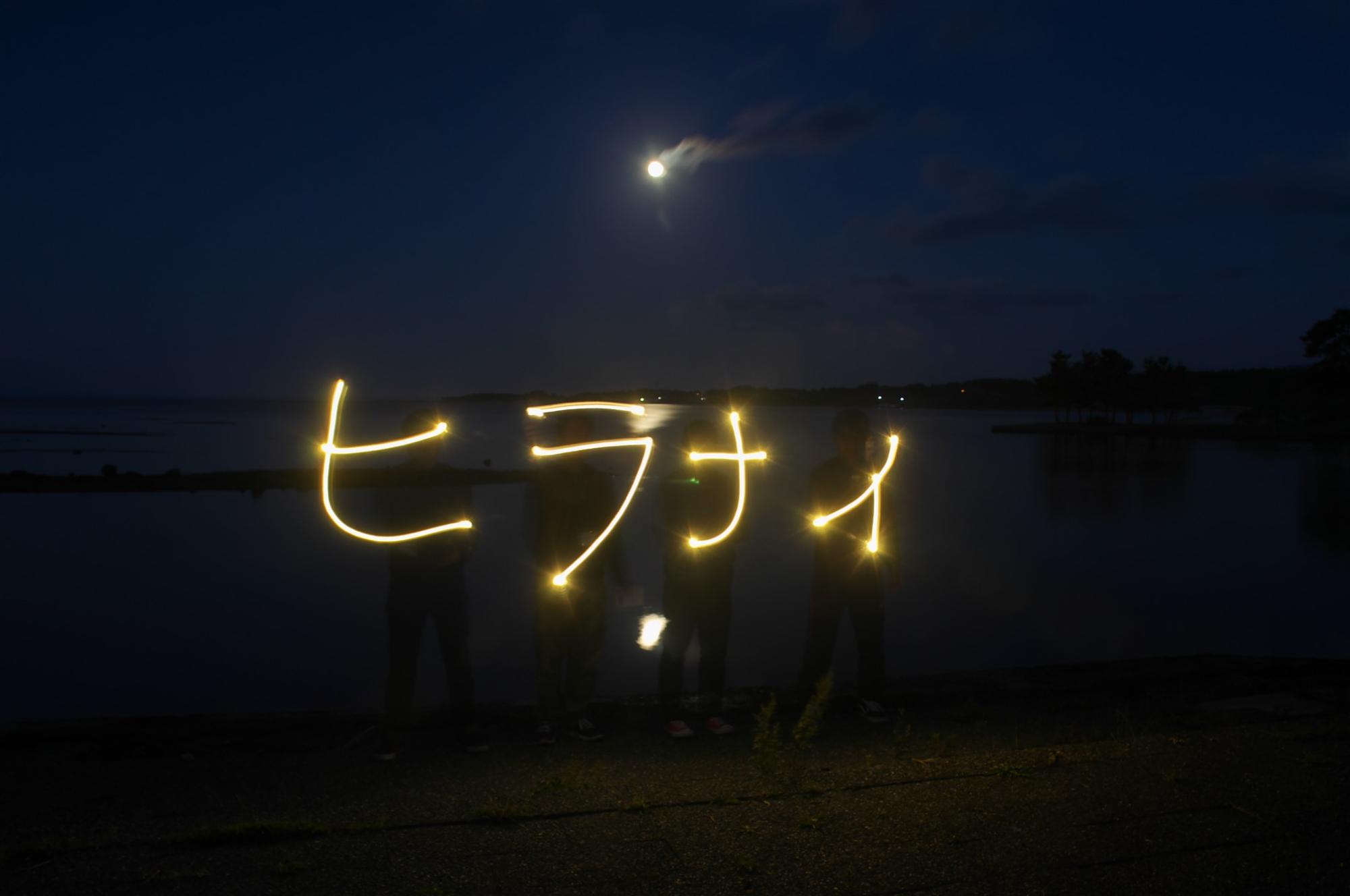 夜空に「ヒラナイ」と書かれたライトアートの写真