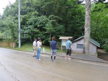 林がそばにある道端で、大学生4人が調査をしている写真