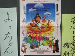 ひまわりの上で動物や女の子が踊っている「よっちゃんの不思議なクレヨン」と書かれたポスターの写真